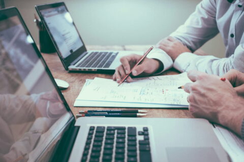 Zwei Personen prüfen Barrierefreiheits-Anforderungen einer Website anhand einer Checkliste neben Laptops.